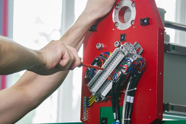 Electrician in overalls is working with energy panel and machinery equipment on plant