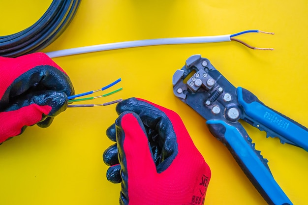 Electrician peeling off insulation from wires - closeup on hands and pliers. selective focus