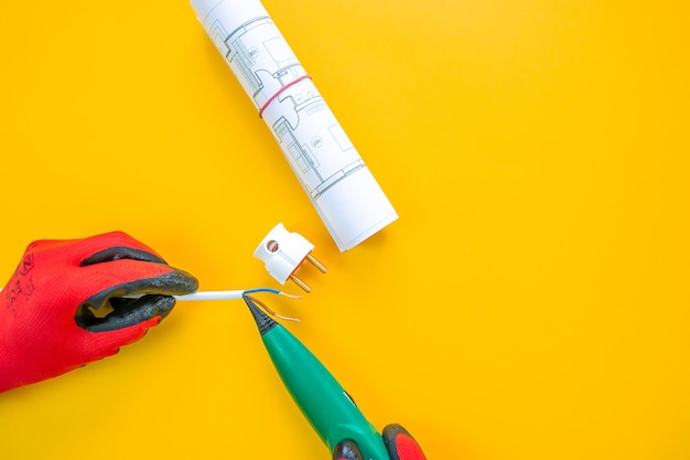 Electrician peeling off insulation from wires - closeup on hands and pliers. Selective focus