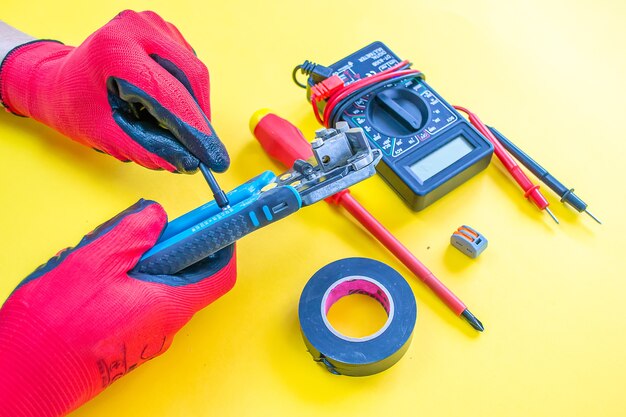 Photo electrician peeling off insulation from wires - closeup on hands and pliers. selective focus