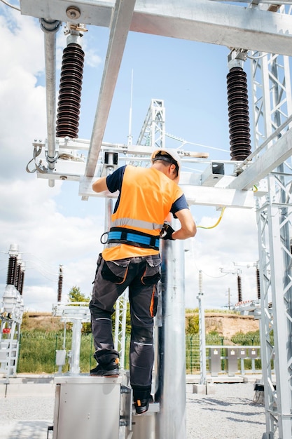 Electrician in protective helmet working on high voltage power lines