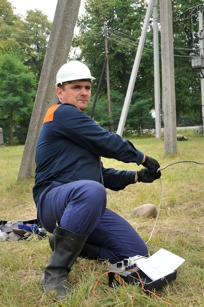 An electrician pulls a wire to ground an electric pole