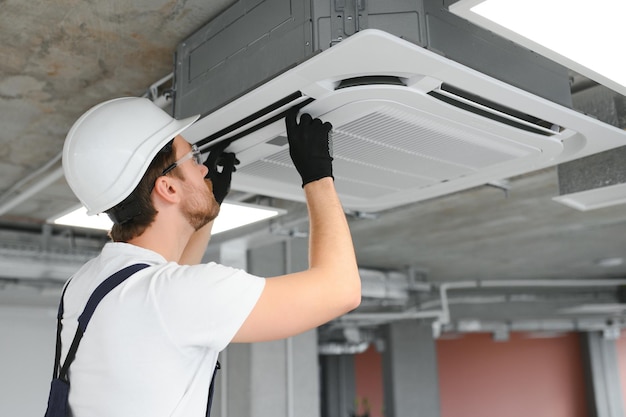 Electrician repairing air conditioner indoors