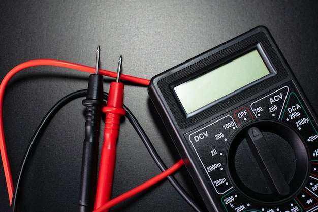 electrician tools on black table, digital multimeter on black table