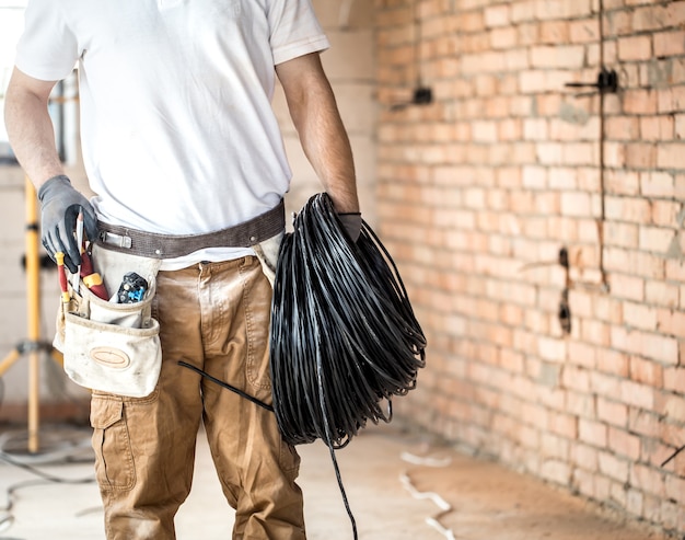 Elettricista con strumenti, lavorando in un cantiere edile