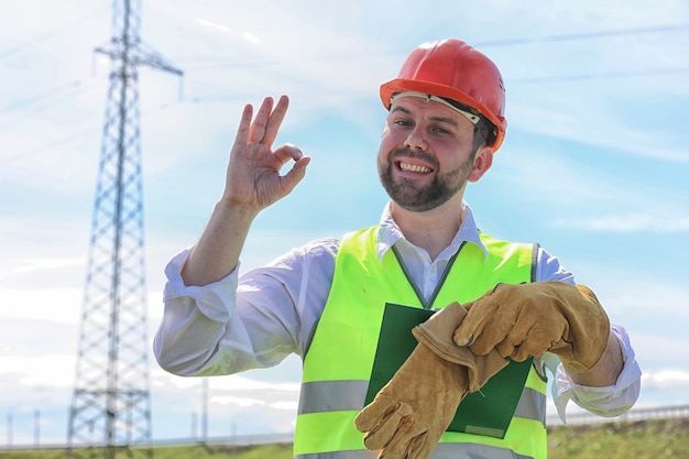 Elettricista che lavora in un casco che indossa guanti in piedi in un campo