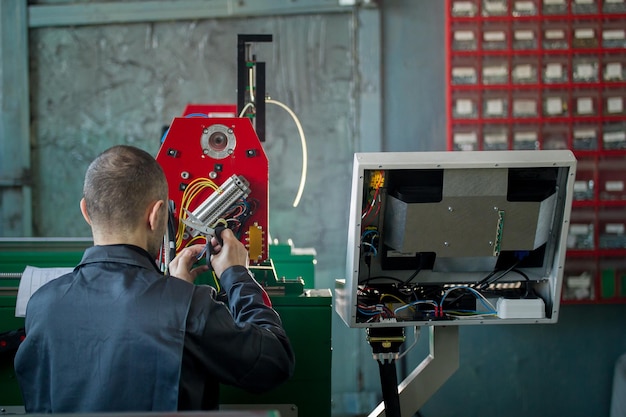 Electrician works with parts of energy equipment on plant, rear view