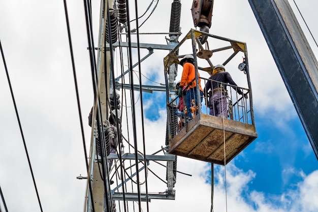 Electricians are climbing on electric poles to install and repair power lines.