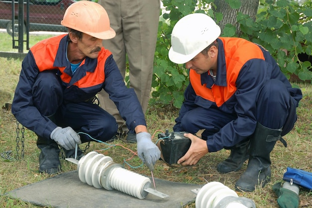 Electricians check the serviceability of the high-voltage insulator before replacing it on the line.