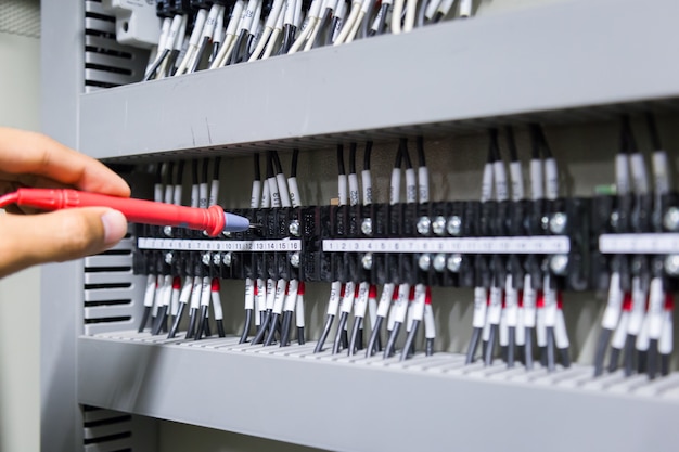 Electricians hands testing current  electric in control panel.