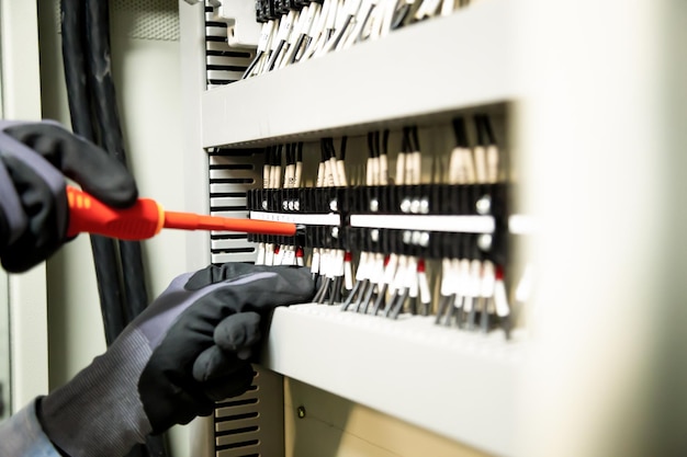 Electricians work to connect electric wires in the system,\
switchboard, electrical system in control cabinet.