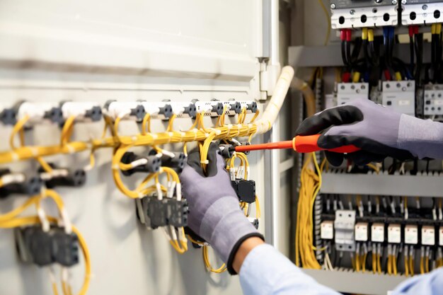 Electricians work to connect electric wires in the system,\
switchboard, electrical system in control cabinet.