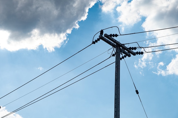 Электричество бетонный столб и высоковольтный провод на фоне голубого неба