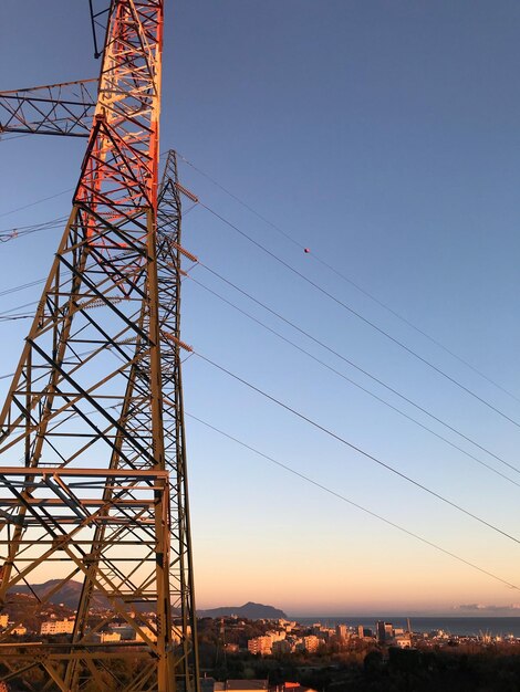 Electricity pylon against clear sky during sunset