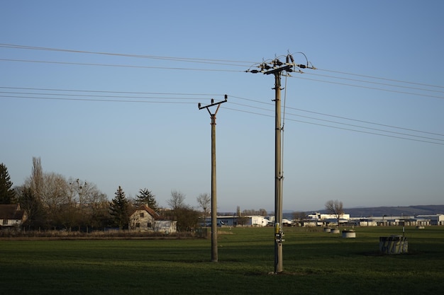 Электрический столб на поле на фоне ясного неба