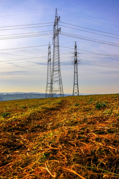 Electricity pylon on field against sky