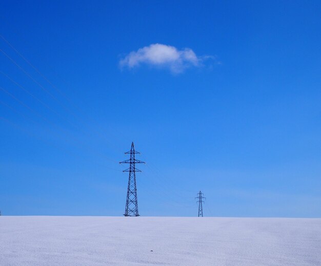 Electricity pylon on landscape against blue sky