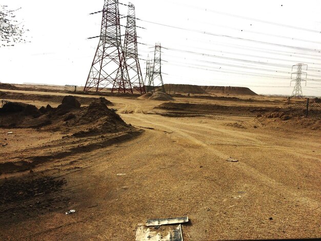 Electricity pylon on road against sky