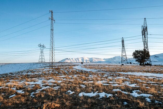 Electricity pylon on snow covered land against sky