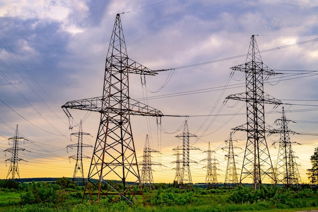 Electricity pylons bearing the power supply across a rural landscape Orange sunset Selective focus