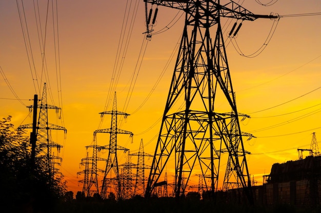 Electricity pylons bearing the power supply across a rural landscape during sunset Selective focus