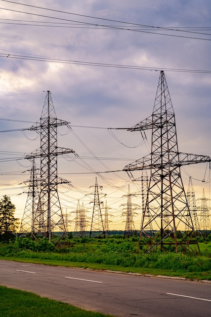 Electricity pylons bearing the power supply across a rural landscape during sunset. Selective focus.