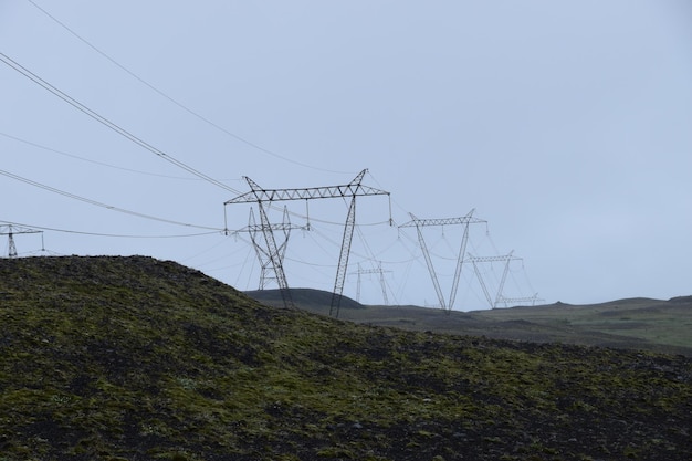 Electricity pylons on field against sky