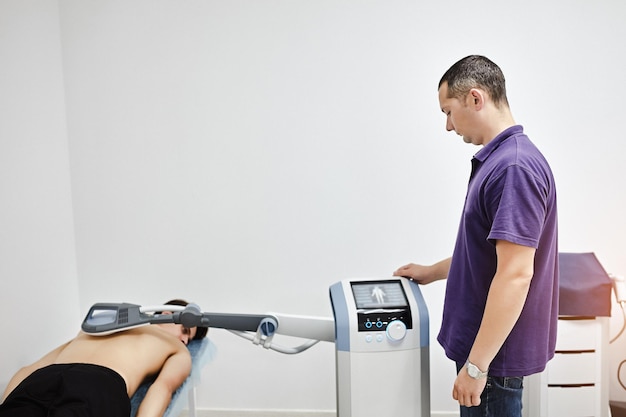 Electromagnetic therapy of the back physiotherapist doctor uses\
medical equipment for highly effective pain treatment and\
inflammation back the magnetic field rehabilitation\
magnetotherapy