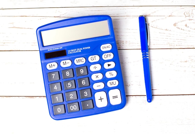 Photo electronic blue calculator blue ballpoint pen on a light wooden table