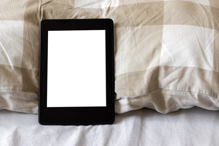 Electronic book with a blank screen on a white and beige bed