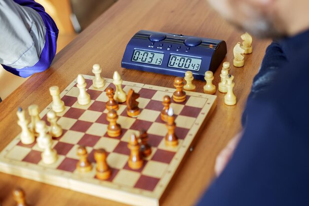 Photo an electronic chess clock and a chessboard with pieces are on the table