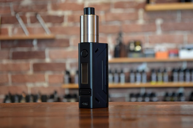 Electronic cigarette on a background of vape shop. E-cigarette for vaping. Popular vape devices