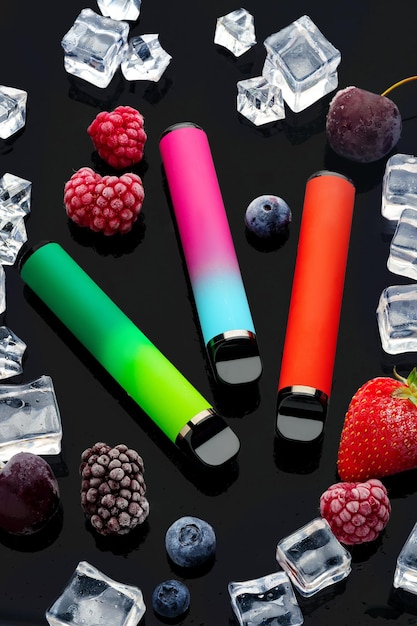 Electronic cigarette with berries and ice cubes on black background