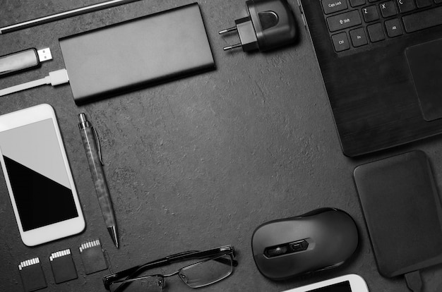 Electronic gadgets on a black concrete background. Concept of accessories for successful business. Flat lay.