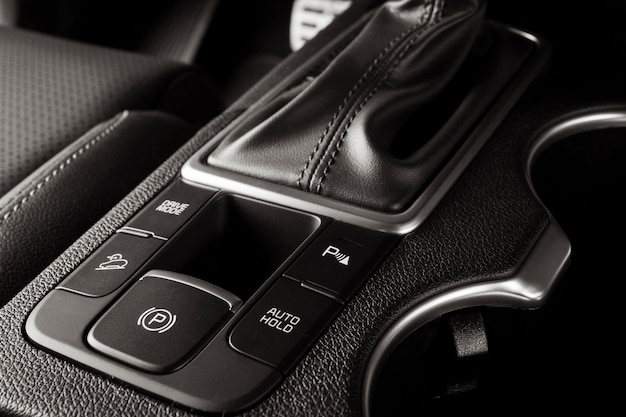 Electronic handbrake button on a new car with luxurious and\
modern details