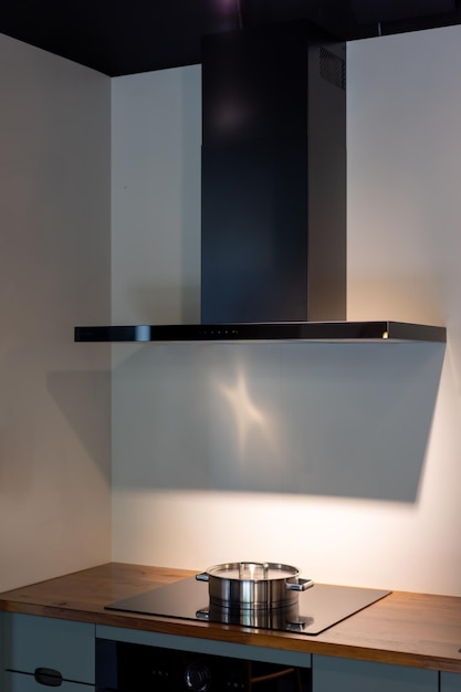 Электронная вытяжка или вентилятор над кастрюлей и духовкой в кухонном углу в условиях низкой освещенности