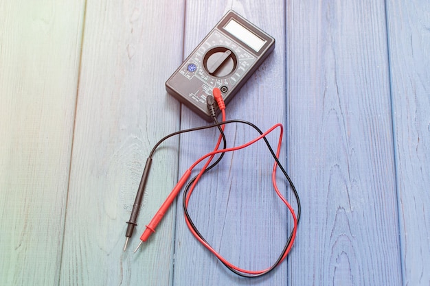 Electronic multimeter to measure the current on a wooden background