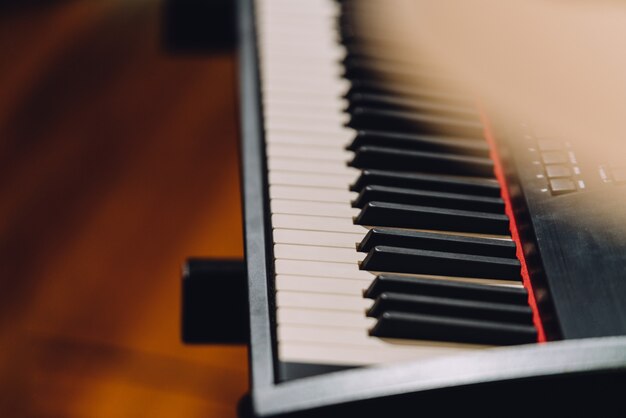 Electronic musical keyboard synthesizer with white and black keys in recording studio.