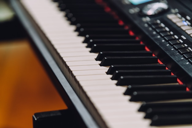 Electronic musical keyboard synthesizer with white and black keys in recording studio