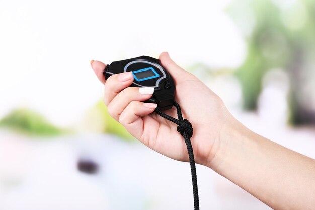 Electronic sport timer in female hand on bright blurred background