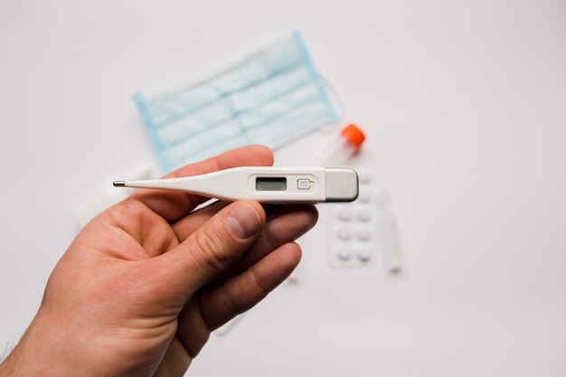 Electronic thermometer in hand with medical mask