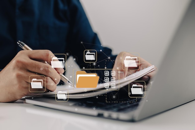 Photo electronicdocumentbased paperless office concept a businessman types while looking at icons for electronic documents on a virtual screen while using a laptop keyboard