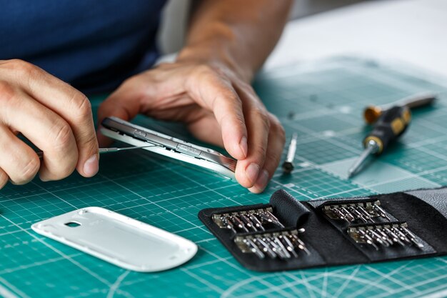 Foto servizio di riparazione elettronica. tecnico che smonta lo smartphone per l'ispezione.