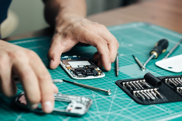 Electronics repair service. Technician disassembling smartphone for inspecting.