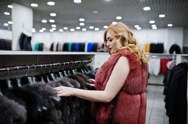 毛皮のコートと革のジャケットの店で毛皮のコートで優雅なブロンドの女の子。