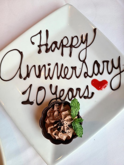 Foto elegante piatto di dessert al cioccolato per il decimo anniversario con torta e menta.