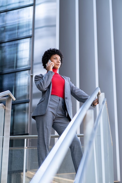 Элегантная афроамериканка разговаривает по телефону в офисном здании на работе
