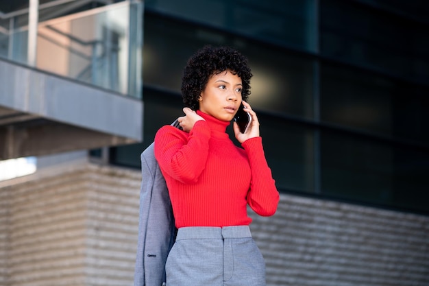 An elegant African American woman using the phone in an office building at work