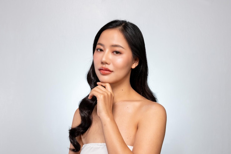 Photo an elegant asian woman poses with her hand on her chin against a grey background