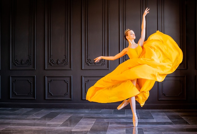 Elegant ballerina in pointe shoes dances in a long yellow skirt